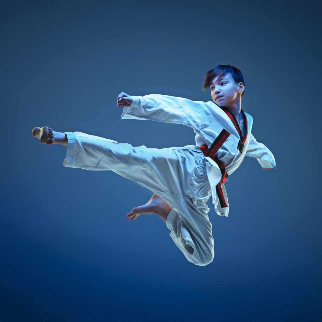 Young boy training karate on blue background