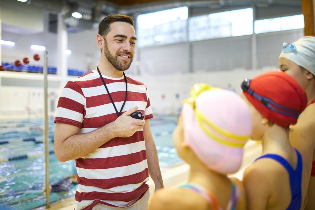 Swim trainer teaching children to swim